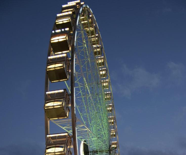 Grande roue illuminée au crépuscule avec ciel bleu foncé.